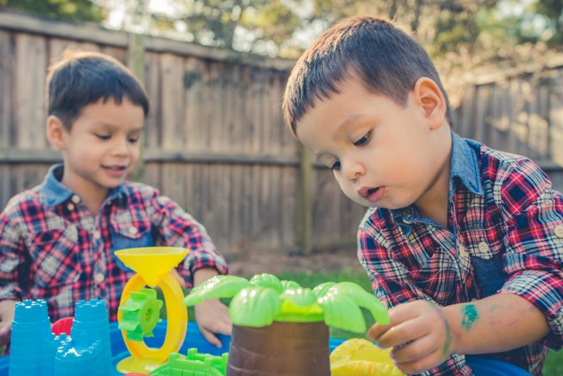 Twee jongens spelen met plastic waterbaan met kasteel en palmboom.