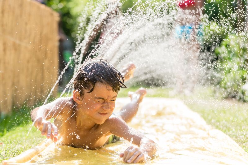 Jongen schuift over buikschuifbaan met water.