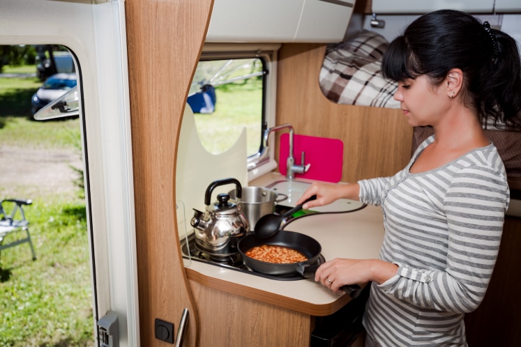 Vrouw kookt bonen in caravan
