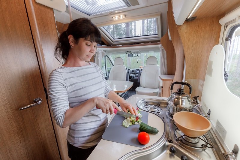 Vrouw kookt in keuken van de camper.