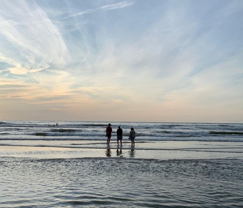 Drie mensen staan in zee