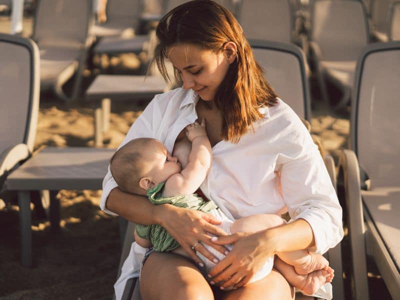 Vrouw geeft borstvoeding op het strand