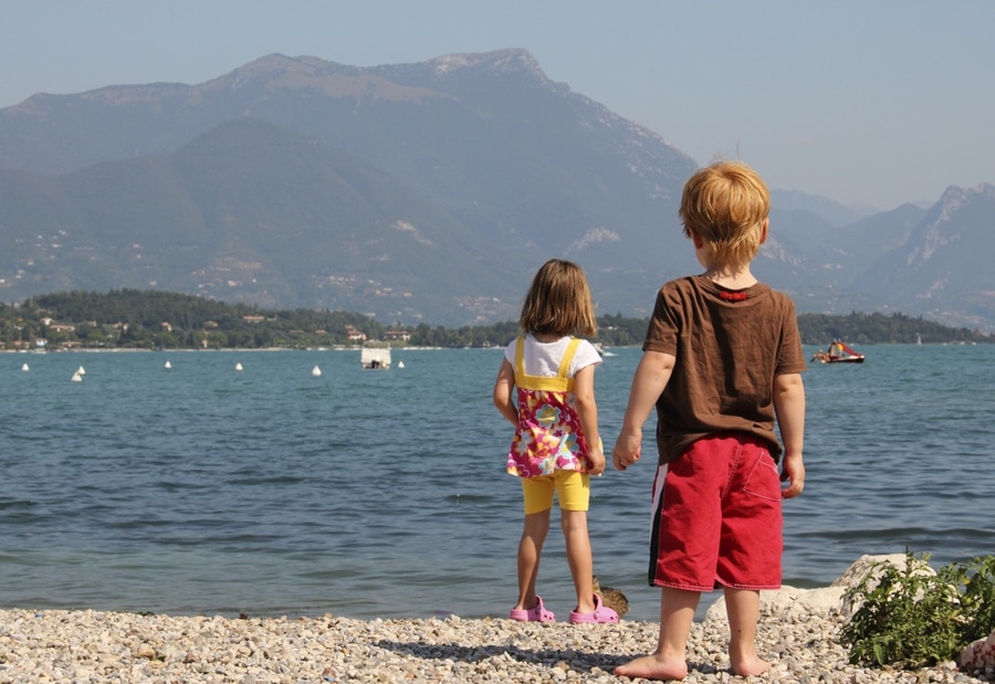 Een jongen en meisje staan aan de rand van het water