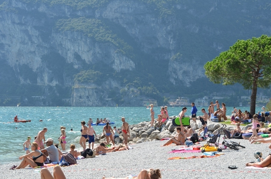 Een strand vol strandgangers met een imposante bergwand op de achtergrond