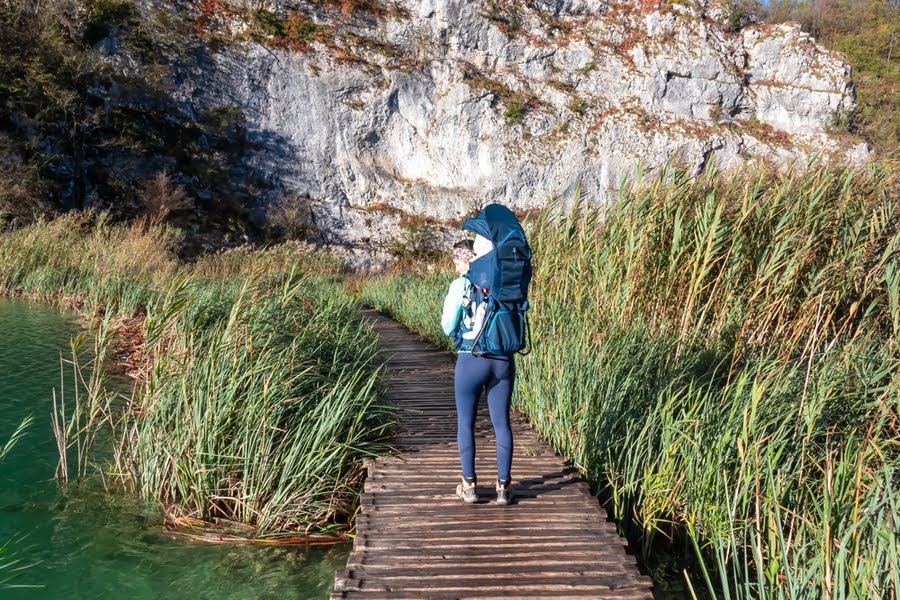 vrouw met baby in draagzak wandelt over vlonderpad