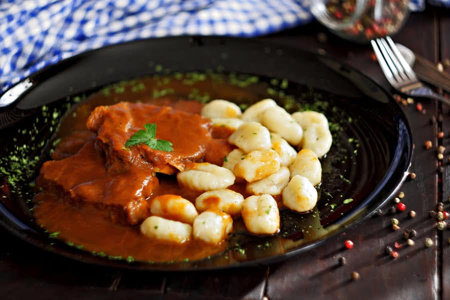 bord met gnocchi en vlees in een bruin sausje