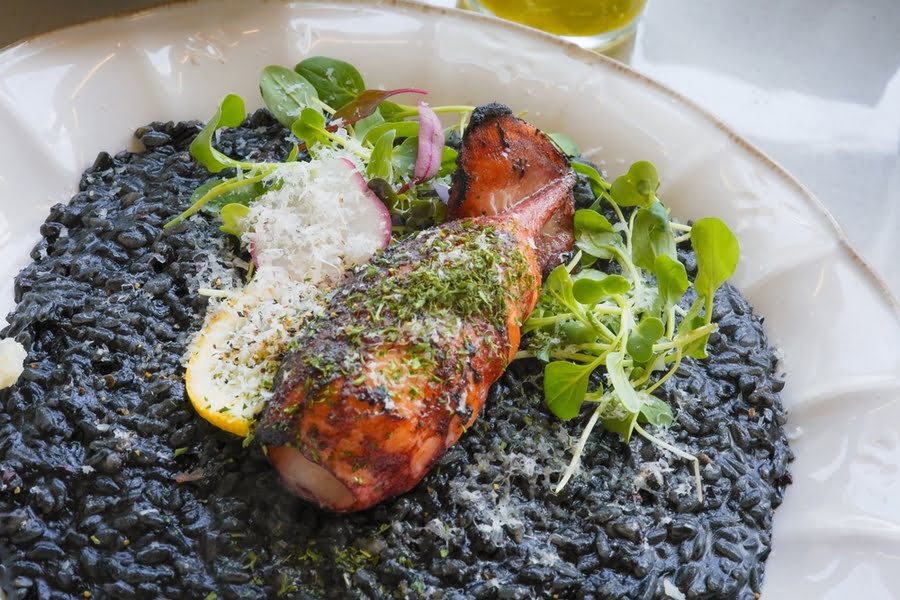 bord met zwarte risotto en bruigebakken inktvis