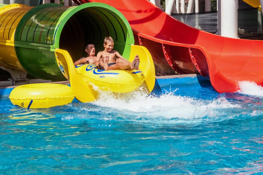 vader en zoon glijden van een waterglijbaan in een rubberbootje